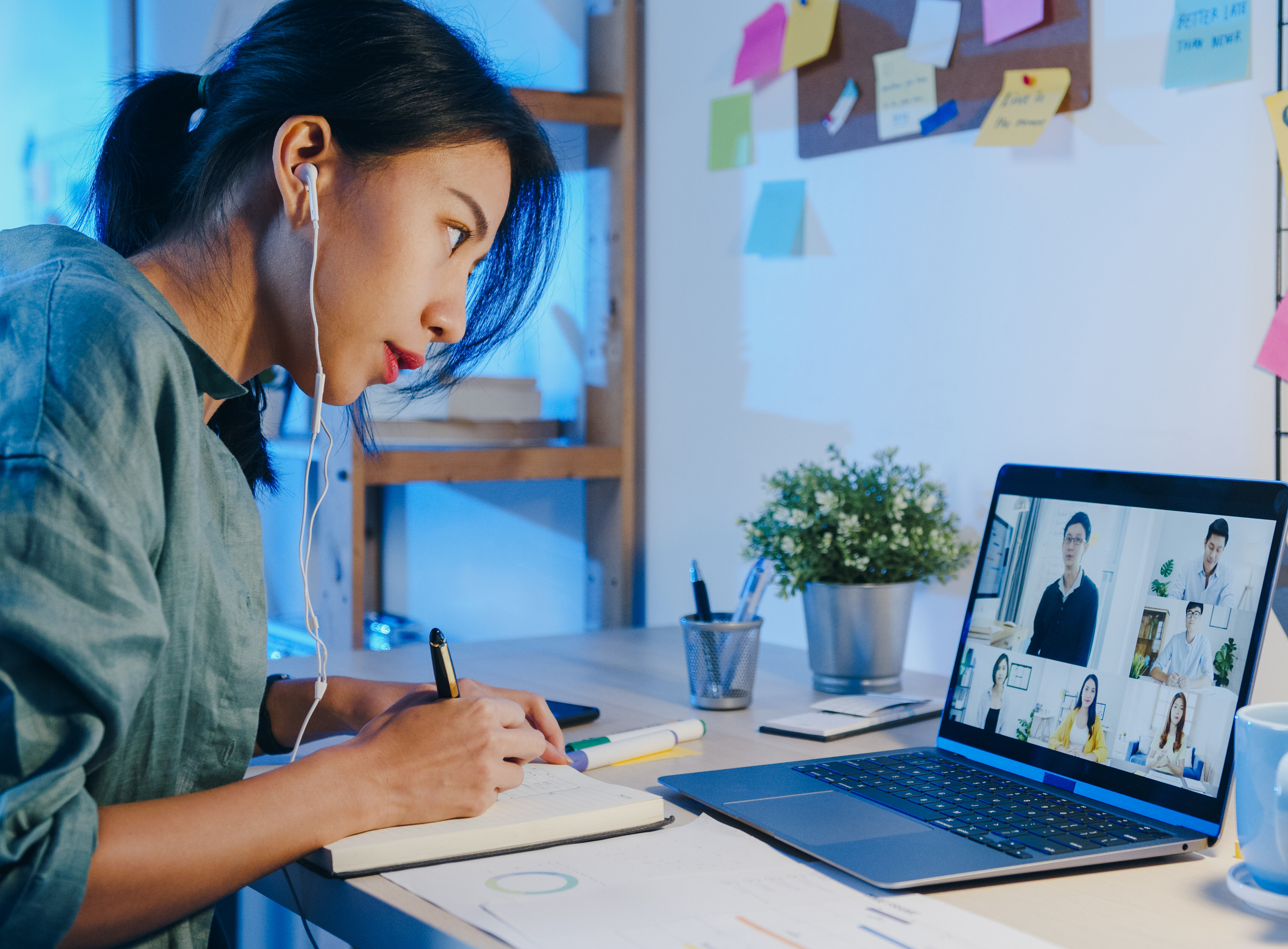 Asia businesswoman using laptop talk to colleagues about plan in video call meeting at living room. Working from house overload at night, remotely work, social distancing, quarantine for coronavirus.