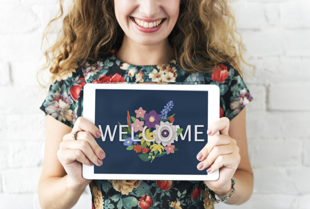 woman holding a tablet that says 'welcome'