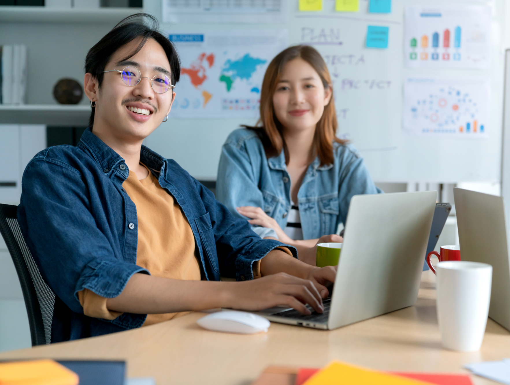 two asian people at work on laptops