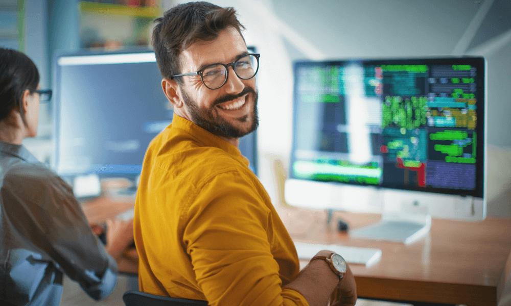 Man smiling at the camera while coding
