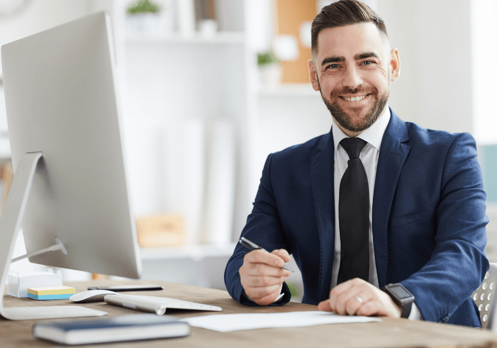 a manager smiling with a laptop on his desk