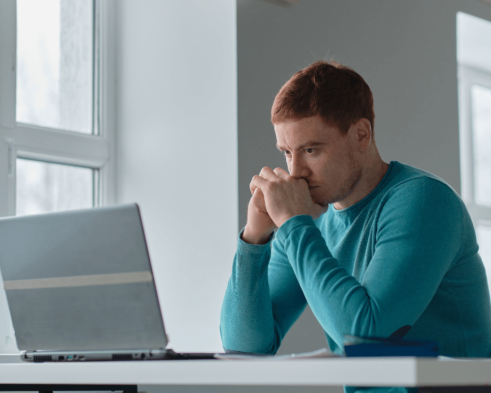a man in deep thought while staring at his laptop