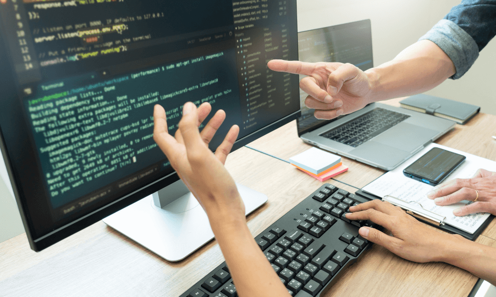 Two people communicating about code on a desktop screen