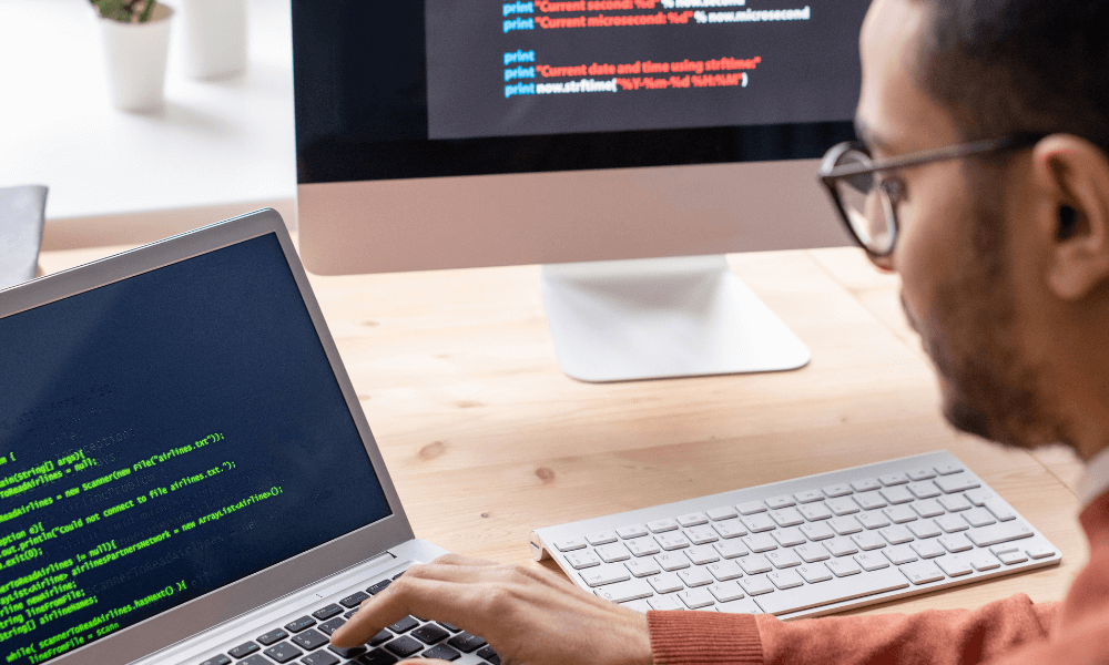 man with glasses looking at code on a computer