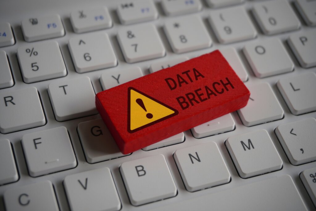 Close up image of computer keyboard and red wooden cube with text DATA BREACH. Internet, technology and network concept