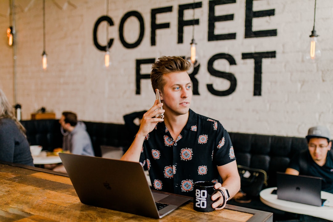 contractor vs employee for small business - A split-screen visual comparing a contractor working independently at a coffee shop with their own laptop versus an employee at a company desk with company equipment, illustrating the core classification distinction